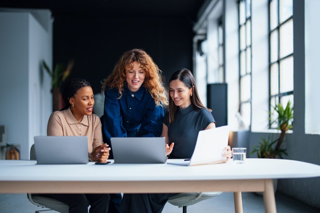 A team of women discussing at a workplace, showcasing collaboration, diversity, and professionalism in an office environment.
